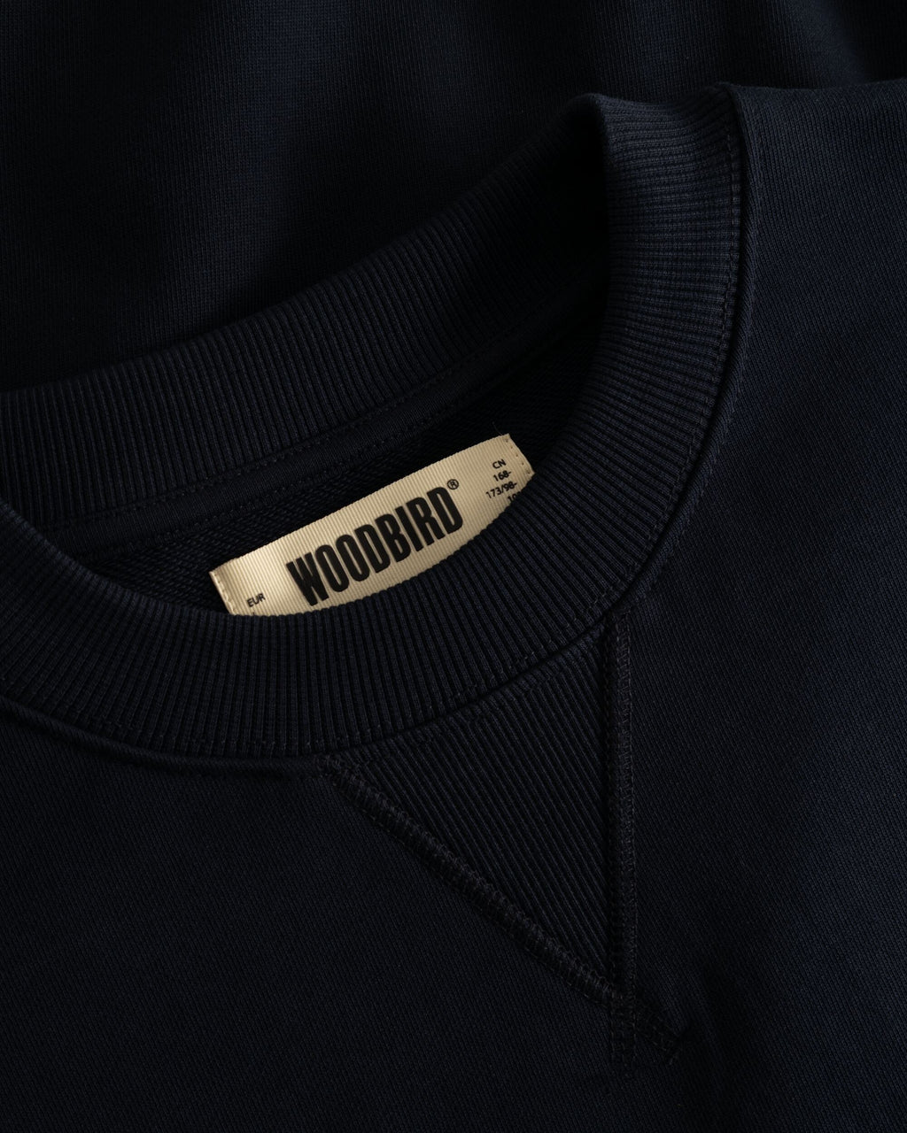 Woodbird WBCane Wok Crew Dark Navy, close-up van het Woodbird label en de afwerking in de halslijn.